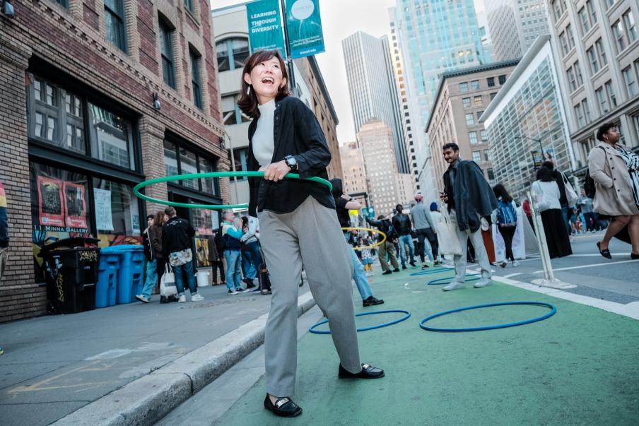 woman in business attire hula hooping on the street at the Downtown First Thursday event