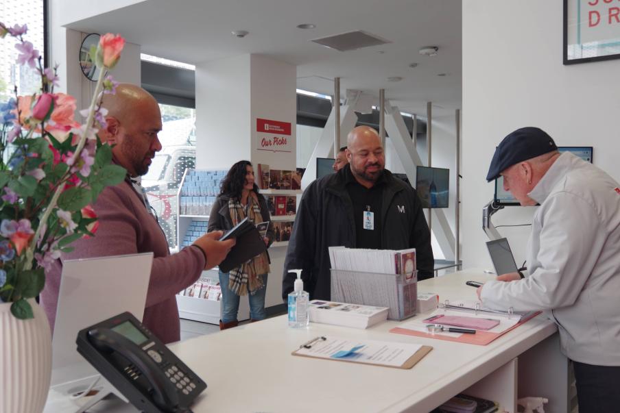Image of the Moscone Visitor Center with a staff member behind the desk sharing information with attendees.